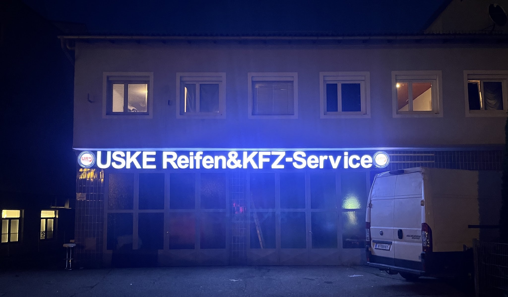 Fassade von Uske Reifen & Kfz Service bei Nacht, beleuchtete Leuchtreklame